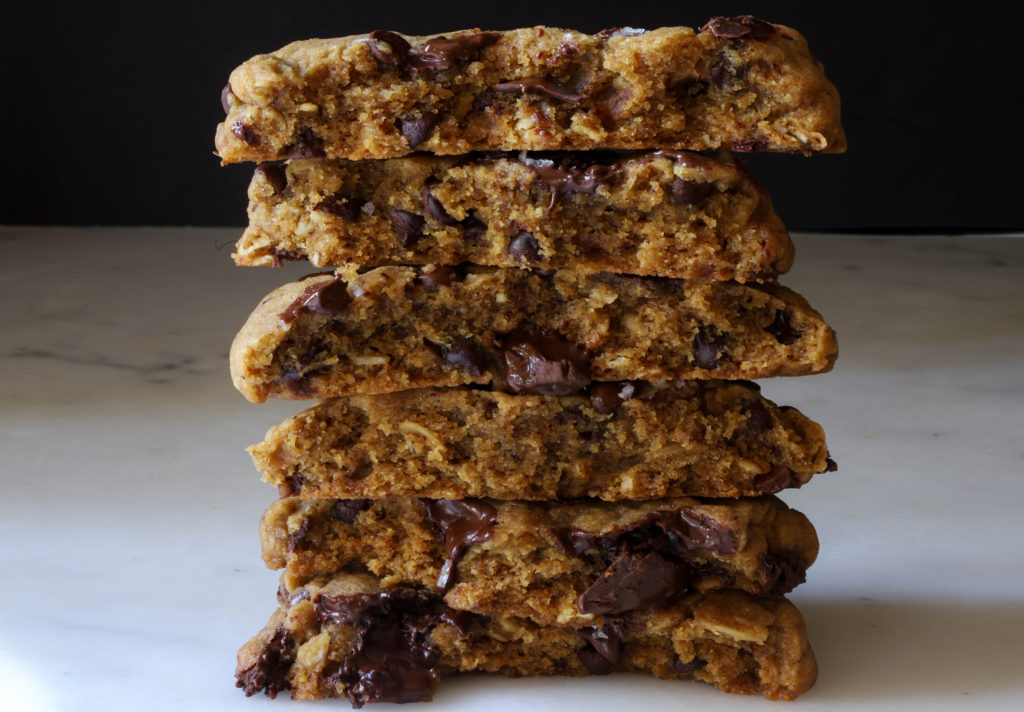 a stack of 6 giant chocolate chunk cookies shows their chewy texture.