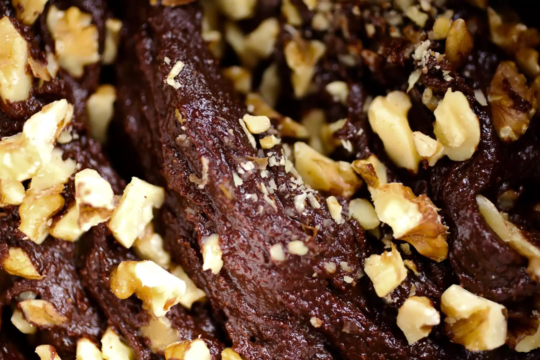 close up of a brownie batter swirl studded with walnuts